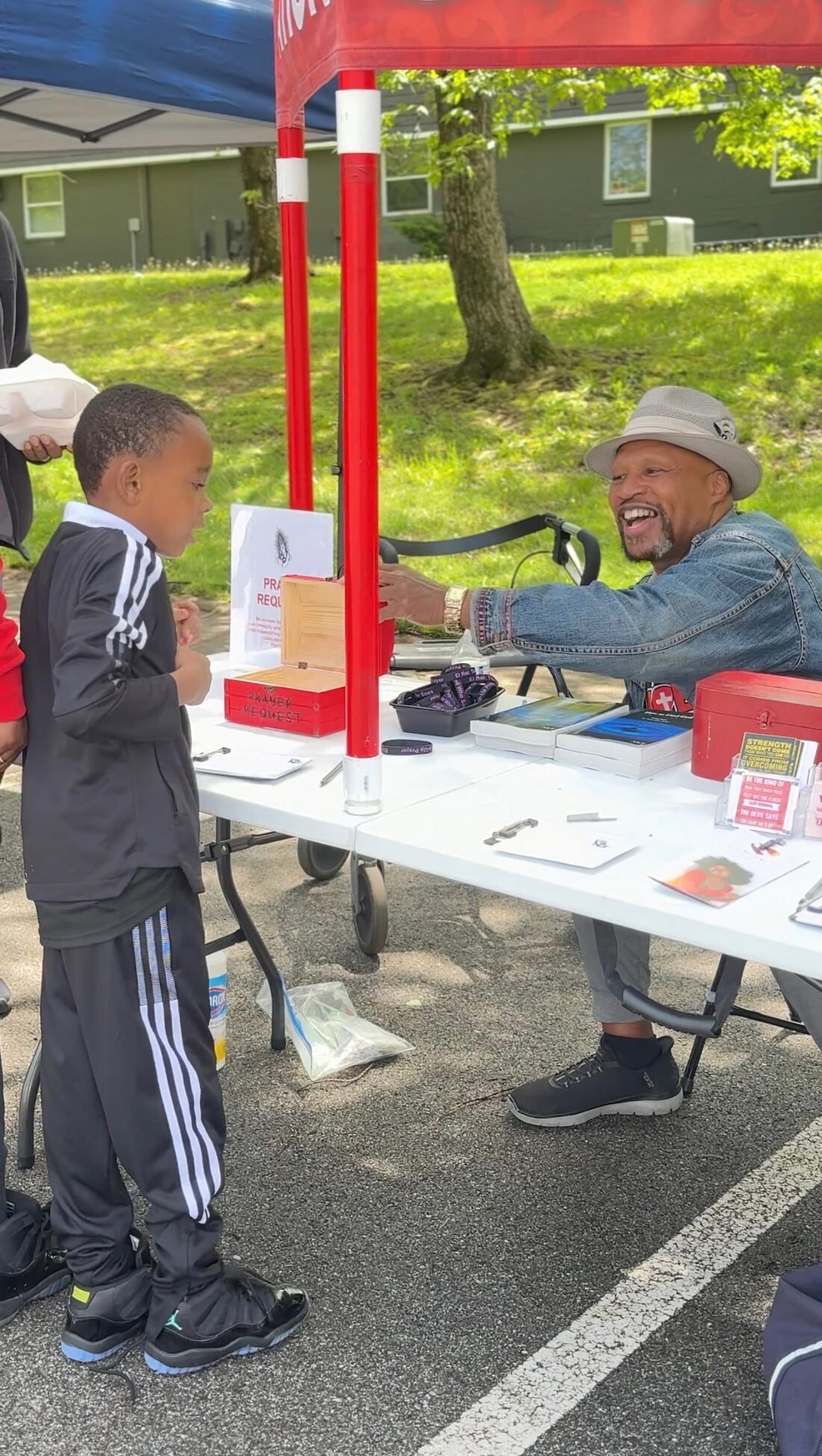 A Roots Foundation volunteer greeting a young boy at a community outreach table