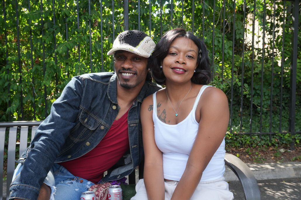A smiling couple sitting on a bench at a community event