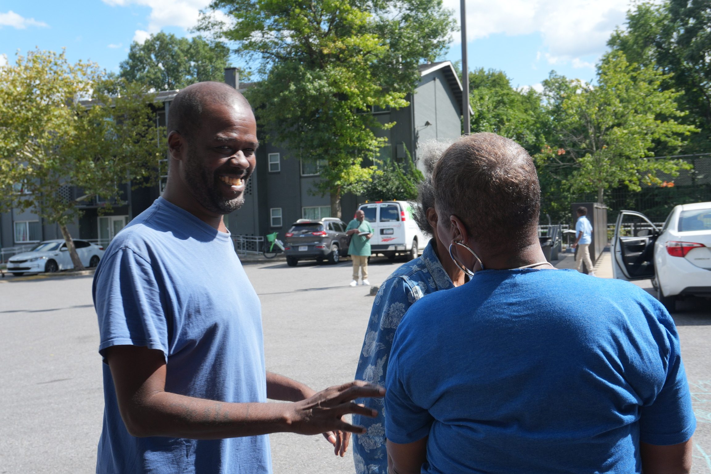 A smiling neighbor talking with community members outside a Roots Foundation event